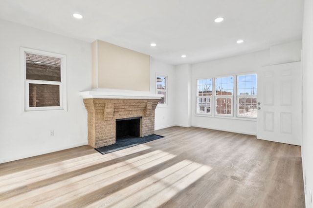 unfurnished living room with light wood-type flooring, a fireplace, baseboards, and recessed lighting