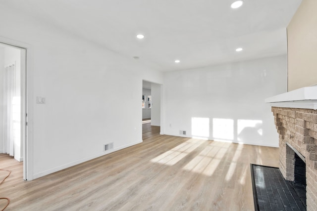 unfurnished living room with light wood-type flooring, a brick fireplace, visible vents, and recessed lighting