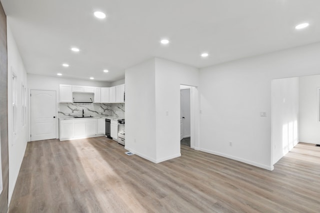 unfurnished living room with recessed lighting, a sink, light wood-style flooring, and baseboards