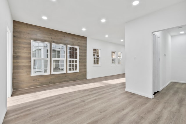 spare room featuring light wood-type flooring, wood walls, baseboards, and recessed lighting