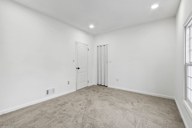 unfurnished room featuring light carpet, visible vents, a wealth of natural light, and baseboards