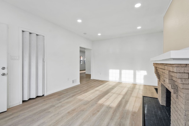 unfurnished living room featuring recessed lighting, visible vents, a brick fireplace, light wood-type flooring, and baseboards