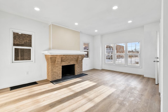 unfurnished living room featuring recessed lighting, visible vents, baseboards, light wood-type flooring, and a brick fireplace