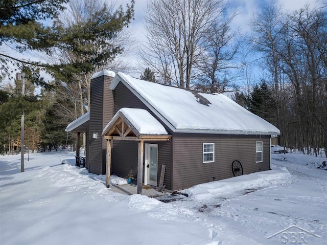 snow covered property featuring a chimney