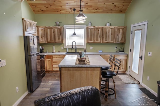 kitchen featuring a kitchen island, decorative light fixtures, freestanding refrigerator, light countertops, and a sink