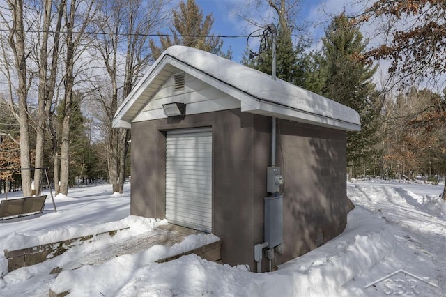 snow covered structure featuring an outbuilding