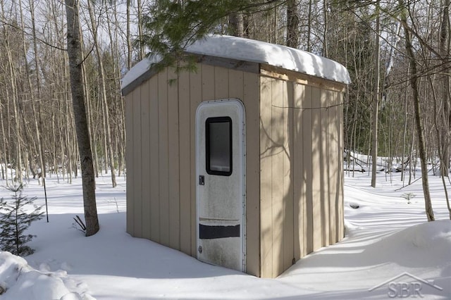 snow covered structure with an outbuilding