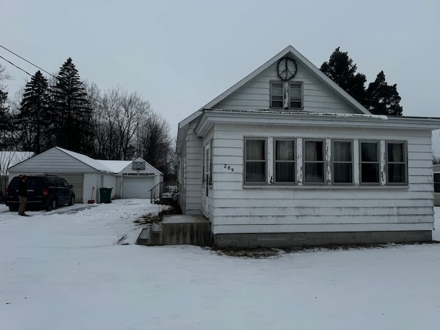 snow covered property featuring a garage and an outdoor structure