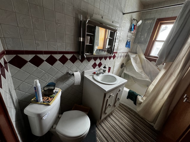 bathroom with tile walls, toilet, shower / bath combo with shower curtain, vanity, and backsplash