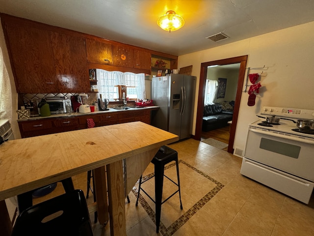 kitchen featuring white electric range, visible vents, backsplash, a sink, and stainless steel fridge with ice dispenser