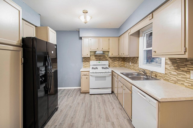 kitchen featuring white appliances, a sink, light countertops, decorative backsplash, and light wood finished floors