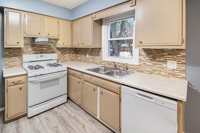 kitchen with wall chimney range hood, light countertops, white appliances, and a sink