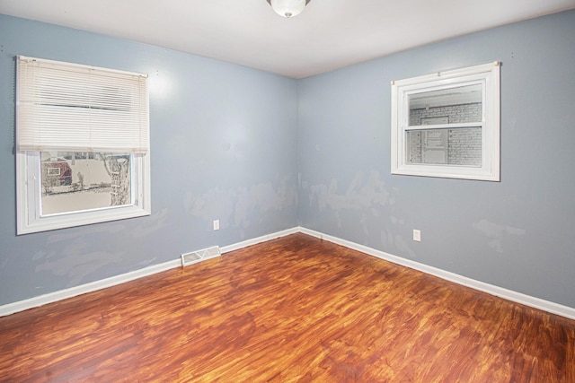 spare room with baseboards, visible vents, and wood finished floors