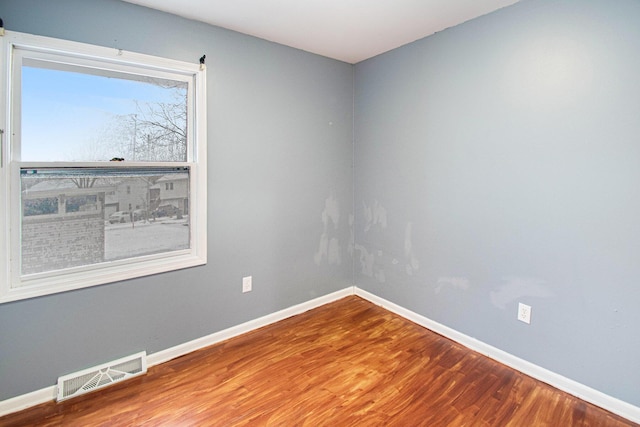 empty room featuring visible vents, baseboards, and wood finished floors