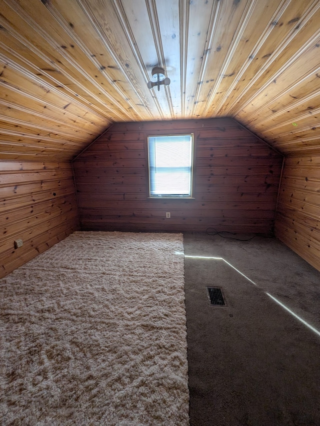 additional living space with wooden walls, carpet floors, wood ceiling, visible vents, and vaulted ceiling