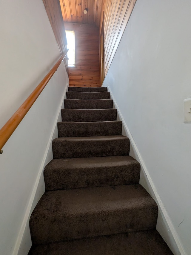 staircase with wood walls and wooden ceiling