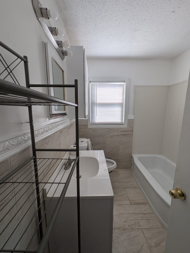 bathroom with a wainscoted wall, tile walls, toilet, a textured ceiling, and vanity