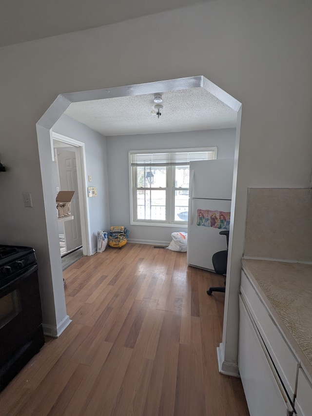 unfurnished dining area featuring visible vents, a textured ceiling, and wood finished floors