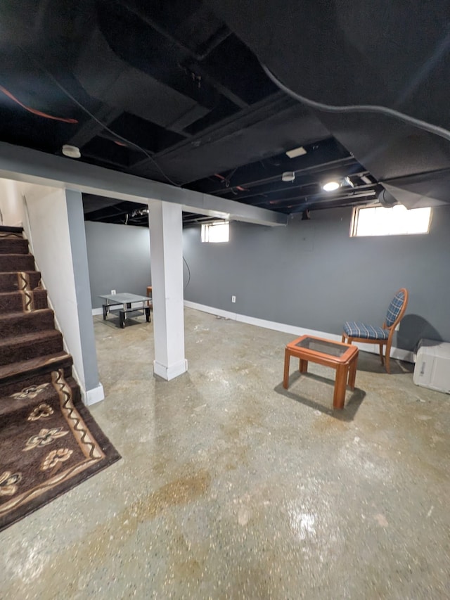 basement featuring baseboards, stairway, and a wealth of natural light