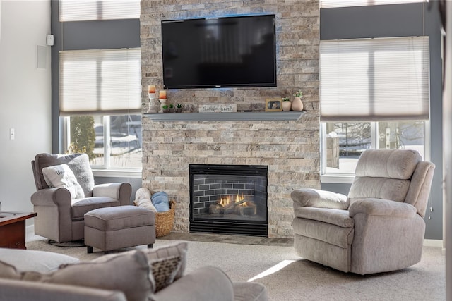 living room with carpet and a stone fireplace