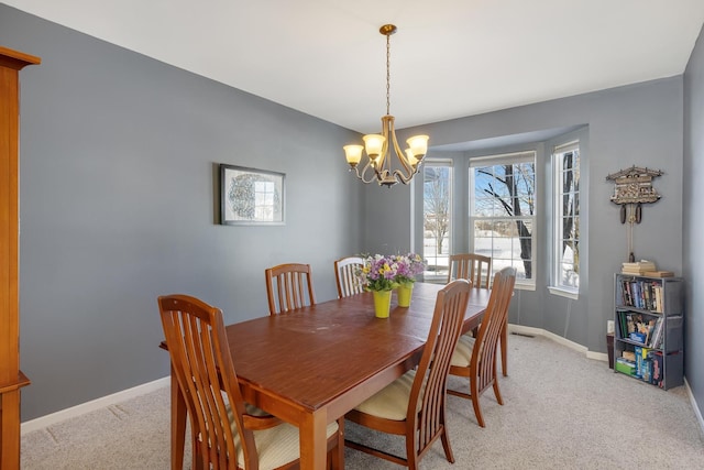 dining room with light colored carpet, baseboards, and an inviting chandelier