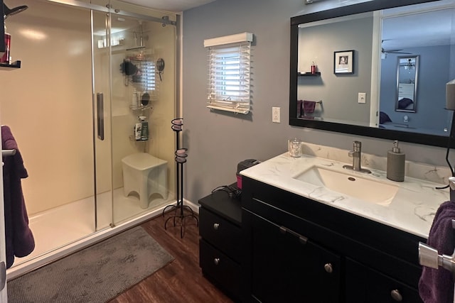 bathroom featuring wood finished floors, a shower stall, and vanity