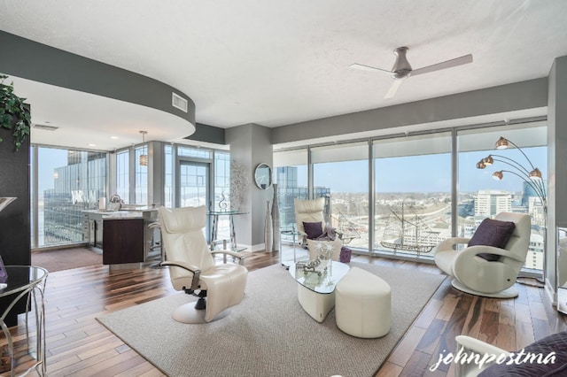 living room featuring a textured ceiling, wood finished floors, visible vents, a ceiling fan, and a view of city