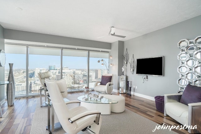 living room with ceiling fan, baseboards, and wood finished floors