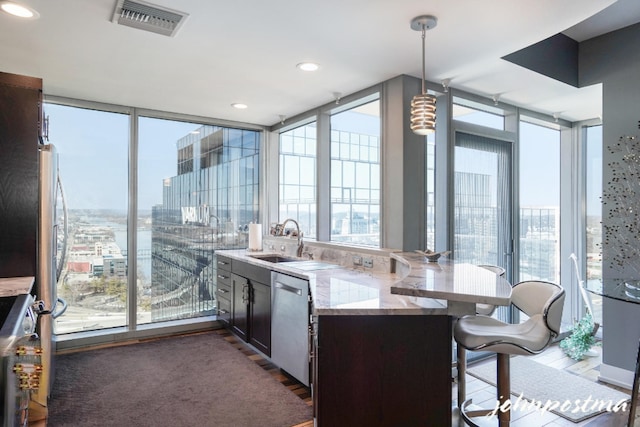 kitchen featuring a view of city, pendant lighting, stainless steel dishwasher, expansive windows, and a sink