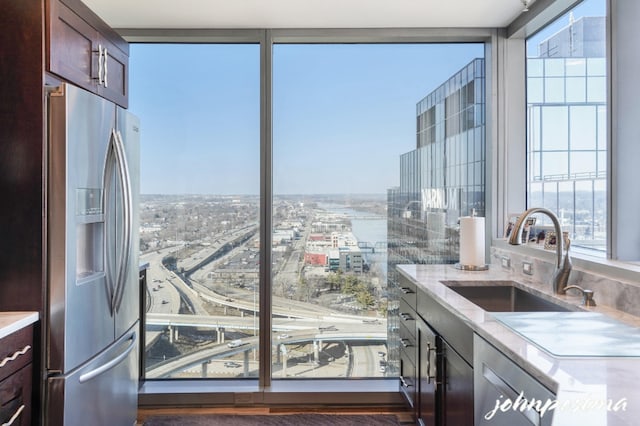 kitchen featuring a healthy amount of sunlight, stainless steel fridge, a view of city, and a sink