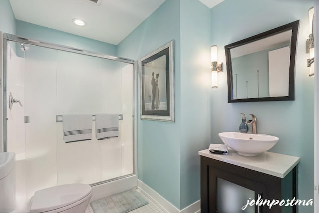 bathroom featuring toilet, a stall shower, vanity, tile patterned flooring, and baseboards