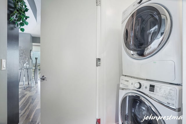 laundry room with laundry area, stacked washer / dryer, and wood finished floors