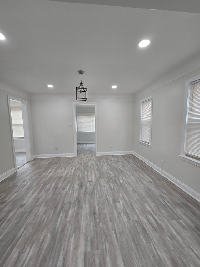 empty room featuring a healthy amount of sunlight, baseboards, and wood finished floors