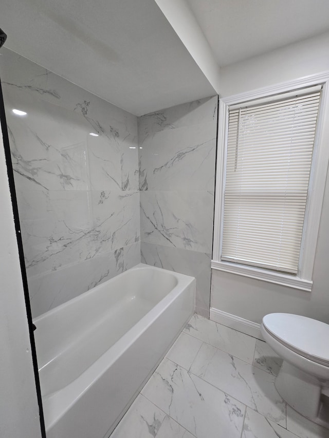 full bath featuring a bath, marble finish floor, toilet, and baseboards