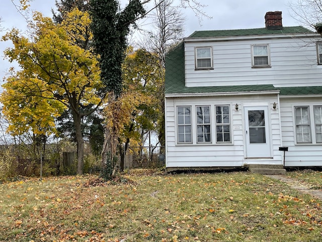 view of front of property with entry steps, fence, and a front lawn