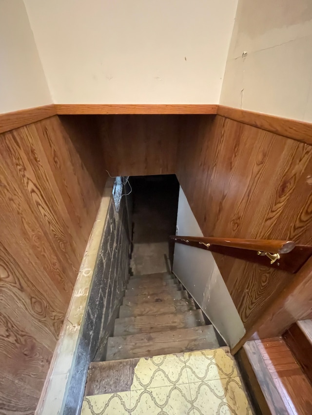 staircase with a wainscoted wall and wooden walls