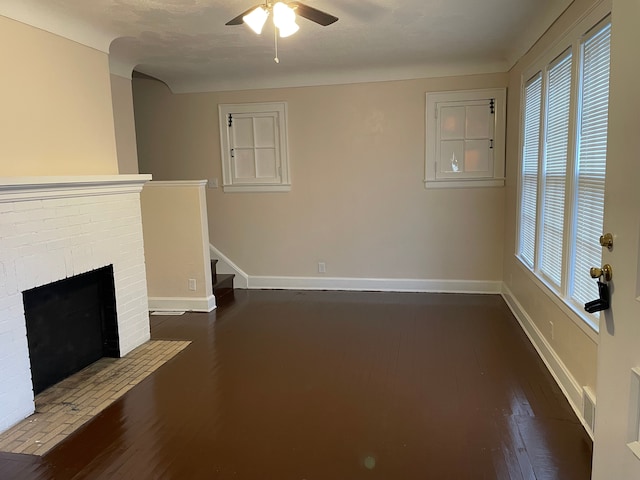 unfurnished living room featuring dark wood finished floors, visible vents, a ceiling fan, a brick fireplace, and baseboards