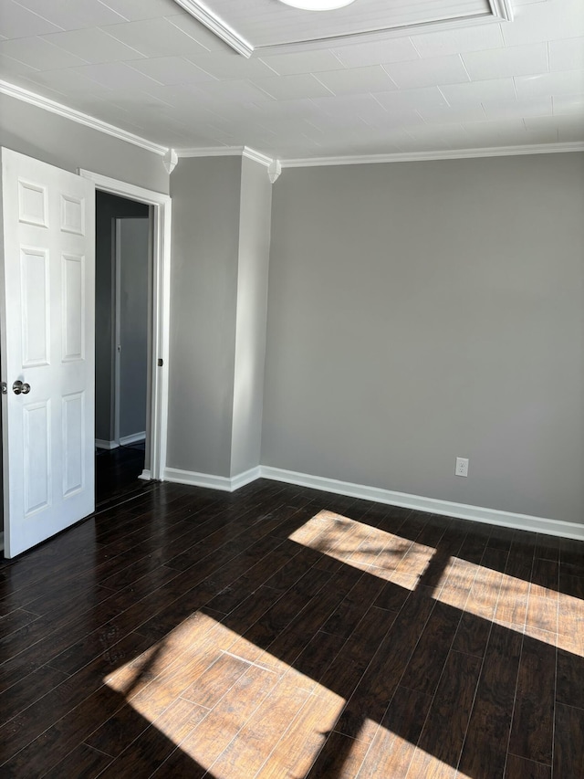 spare room with ornamental molding, dark wood-style flooring, and baseboards