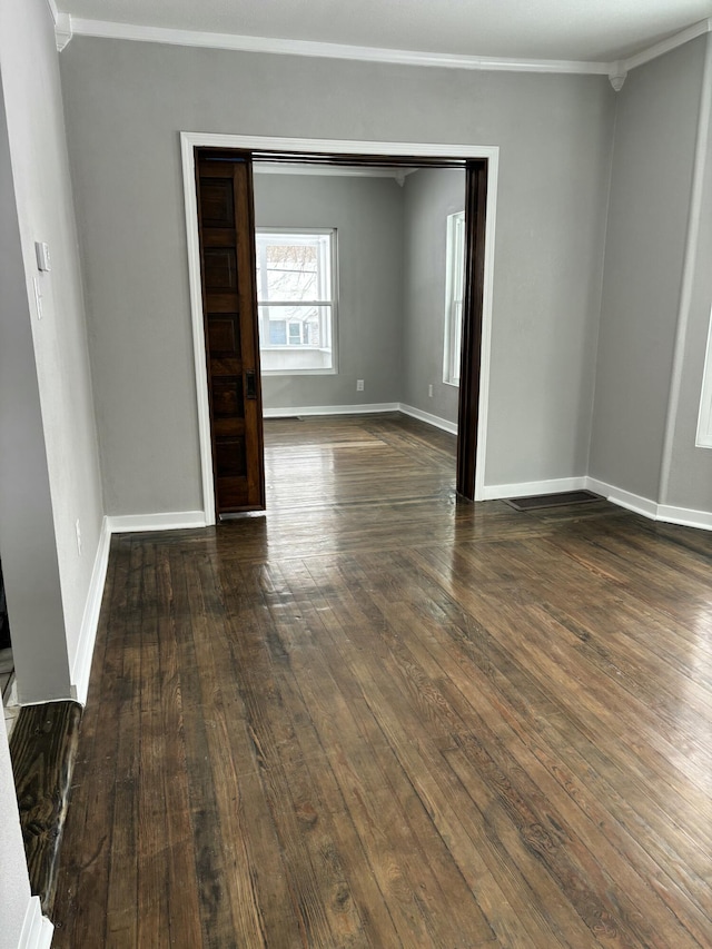 spare room with baseboards, ornamental molding, and dark wood-style flooring