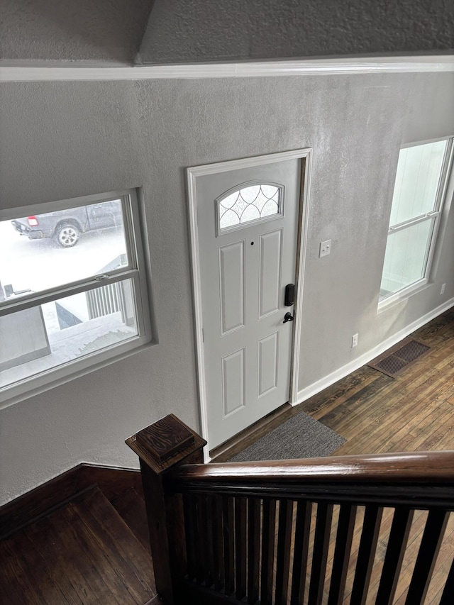 entrance foyer with dark wood-style floors, a textured wall, and visible vents