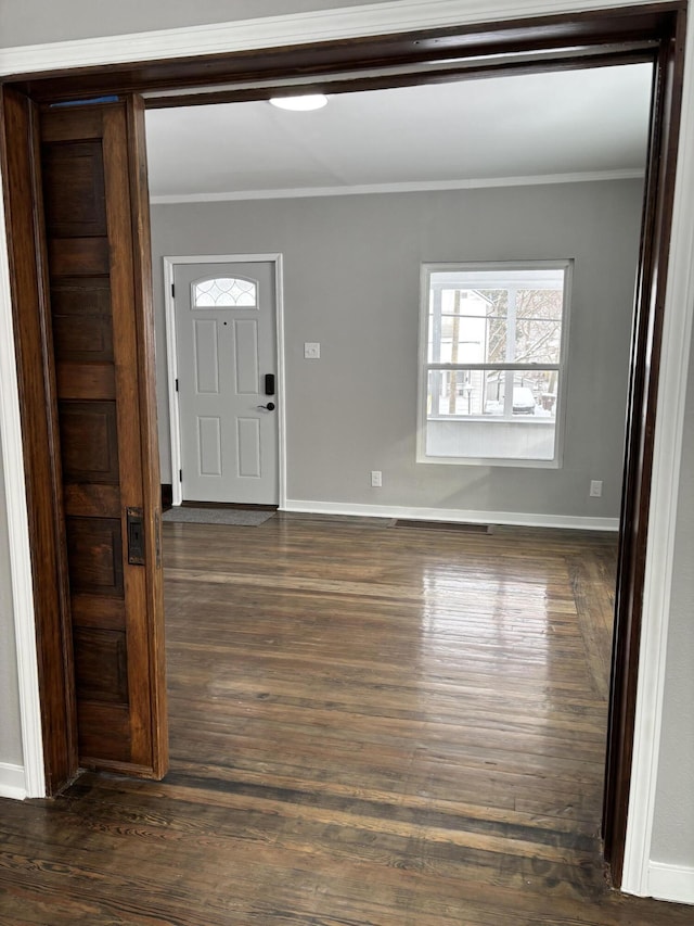 foyer entrance featuring baseboards, dark wood-type flooring, and crown molding