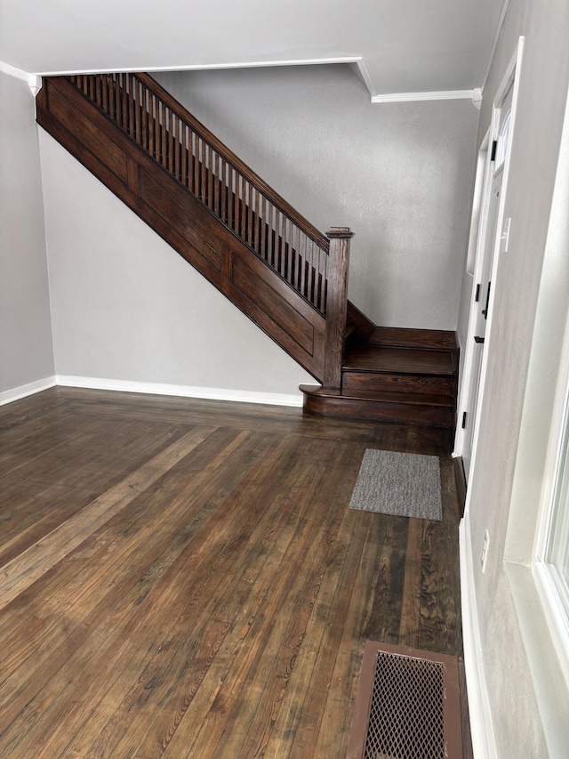 staircase with ornamental molding, wood-type flooring, visible vents, and baseboards