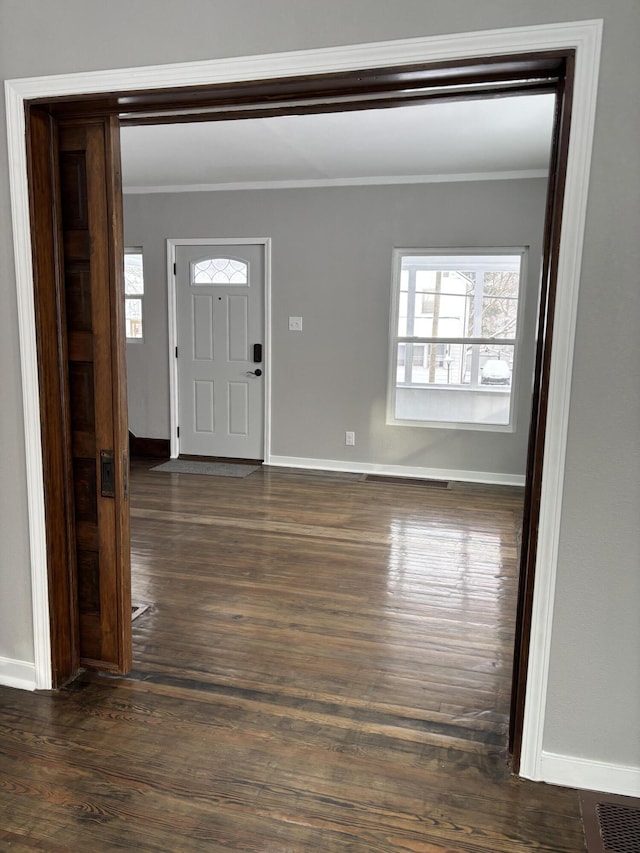 foyer featuring ornamental molding, dark wood-style flooring, and baseboards