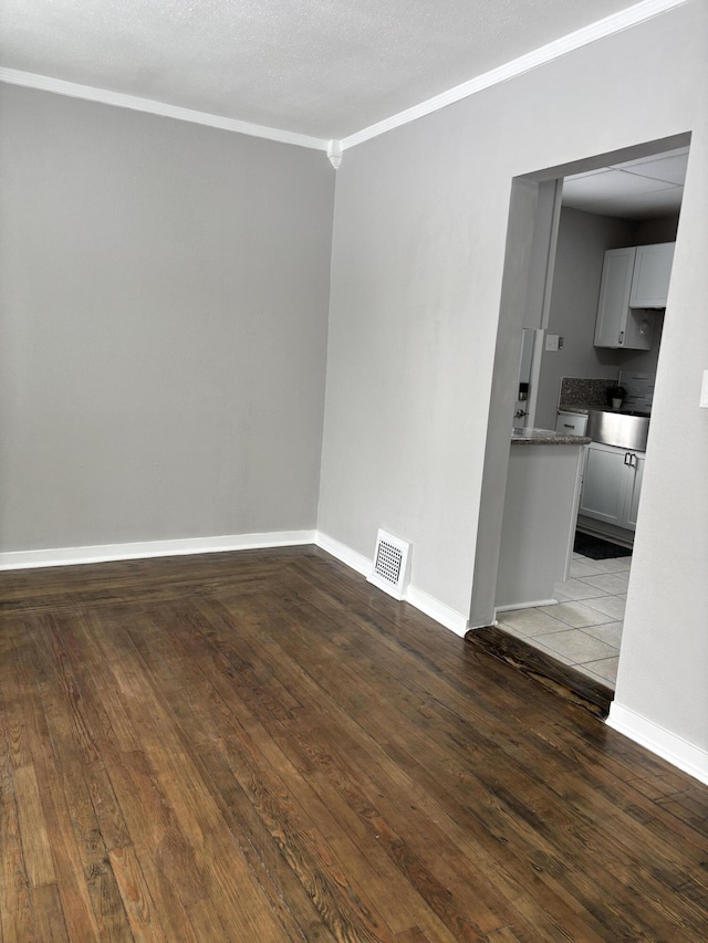 unfurnished room featuring a textured ceiling, visible vents, baseboards, light wood finished floors, and crown molding