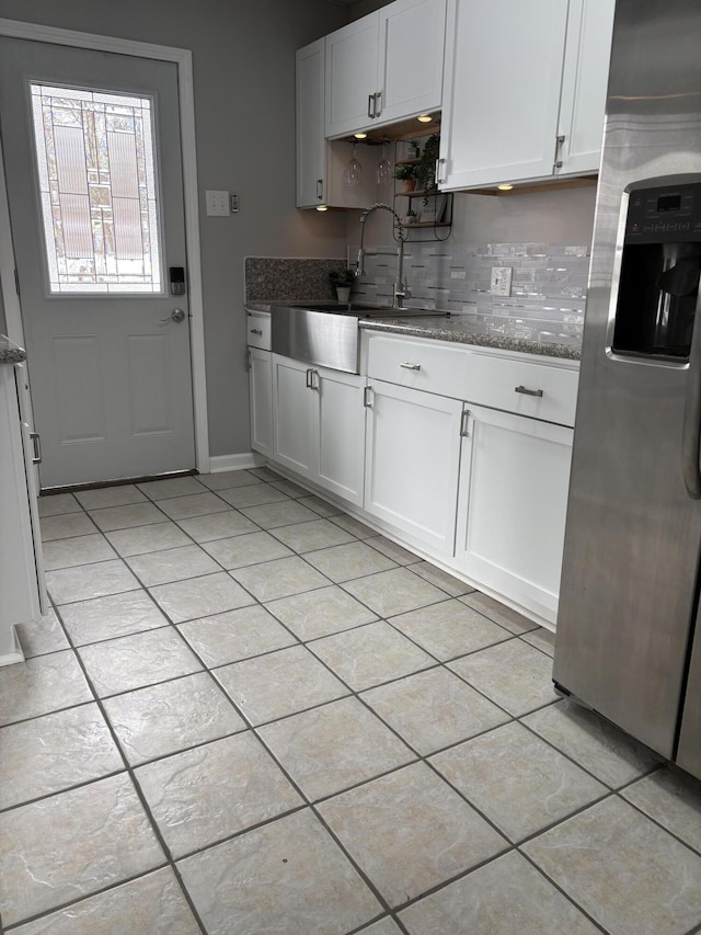 kitchen featuring tasteful backsplash, stainless steel fridge with ice dispenser, white cabinetry, a sink, and light tile patterned flooring