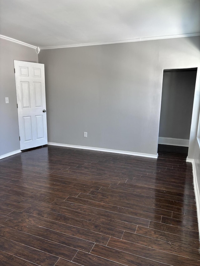 unfurnished room featuring dark wood finished floors, crown molding, and baseboards