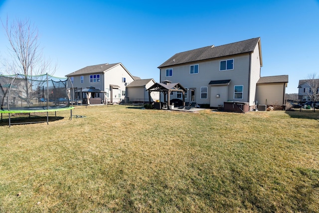 rear view of house featuring central AC unit, fence, a gazebo, a lawn, and a trampoline