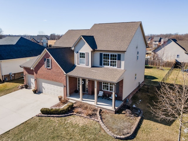 traditional home with brick siding, a porch, concrete driveway, an attached garage, and fence