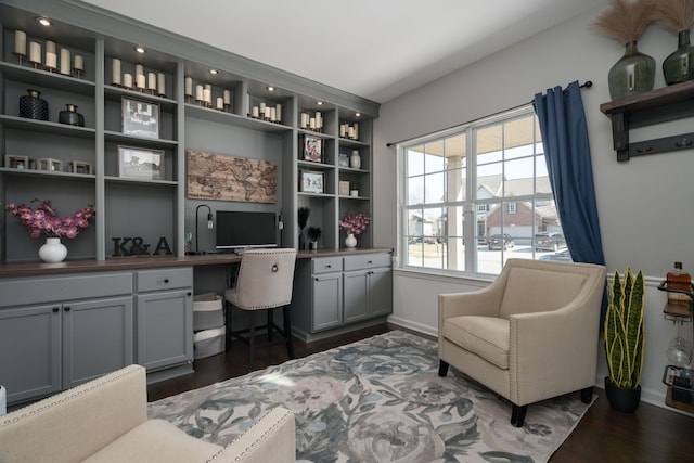 office space featuring built in desk, dark wood finished floors, and baseboards