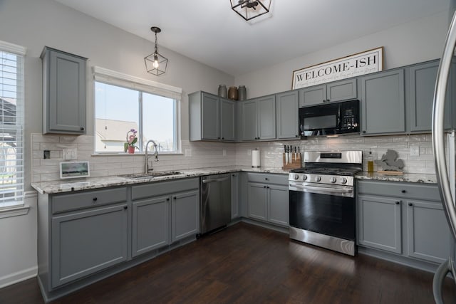 kitchen featuring light stone counters, gray cabinets, appliances with stainless steel finishes, dark wood-type flooring, and a sink